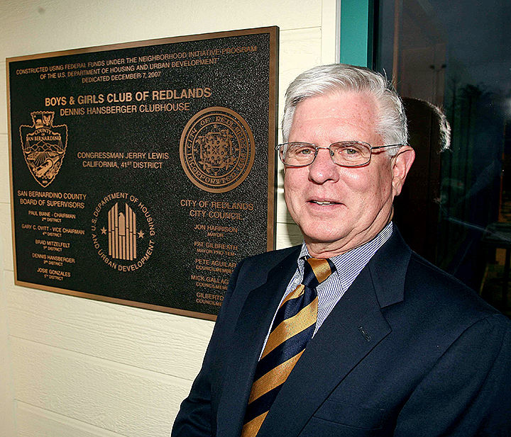 Supervisor Dennis Hansberger poses next tp a plaque outside the Hansberger Clubhouse.